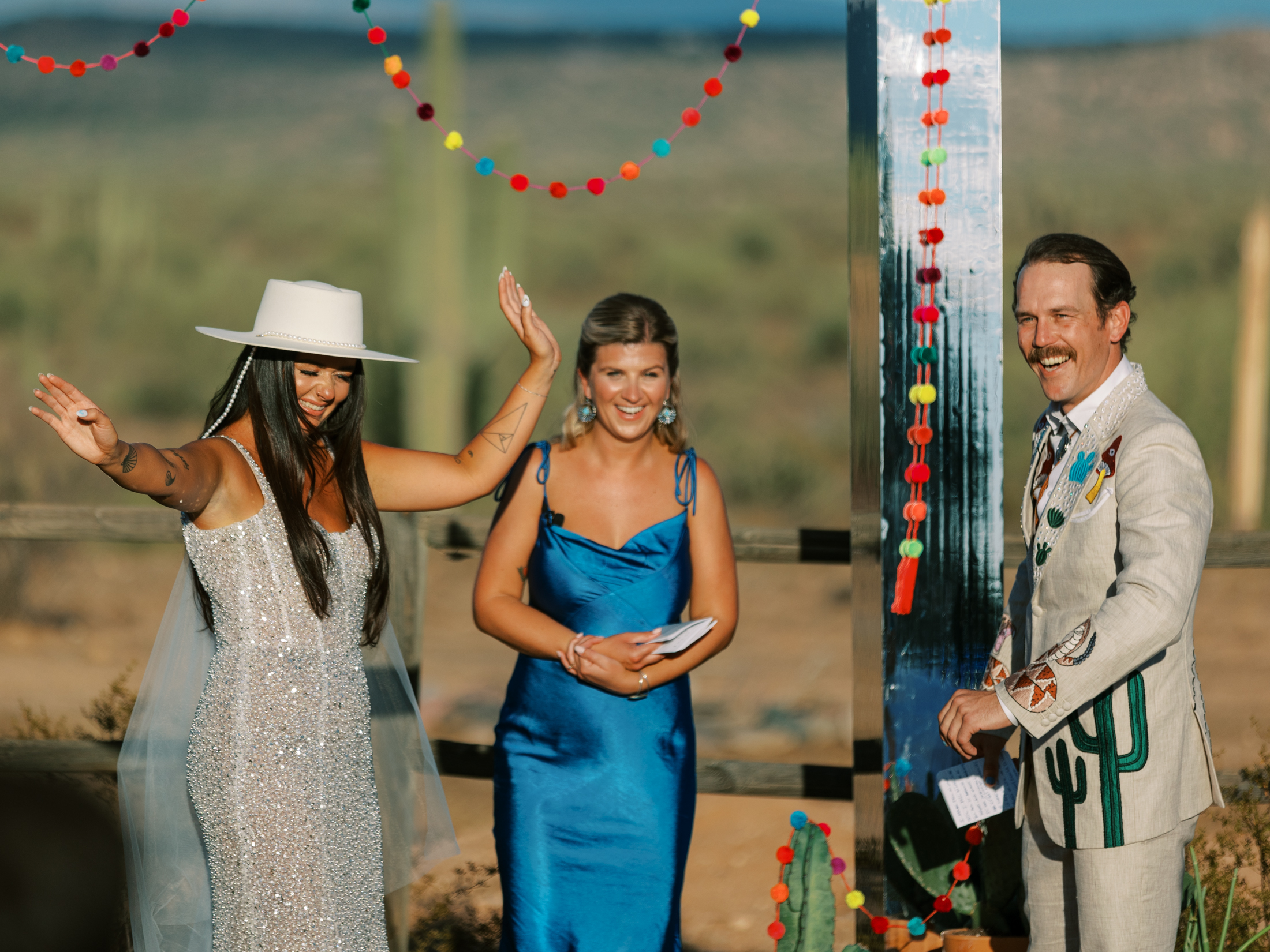 LGBTQ couple rejoicing at their ceremony with mirrored arch and colorful decor in the desert